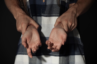 Man holding woman's hands on dark background, closeup. Stop sexual assault