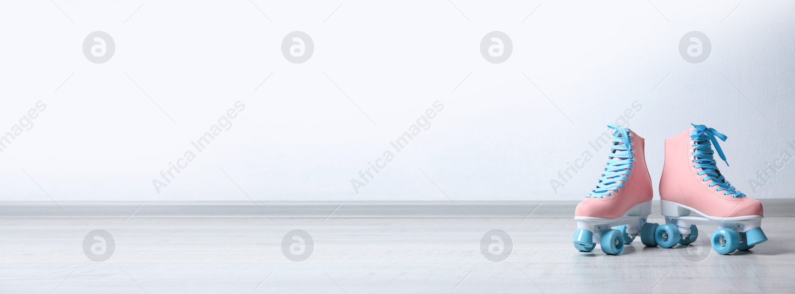 Image of Vintage roller skates on floor near white wall, space for text. Banner design