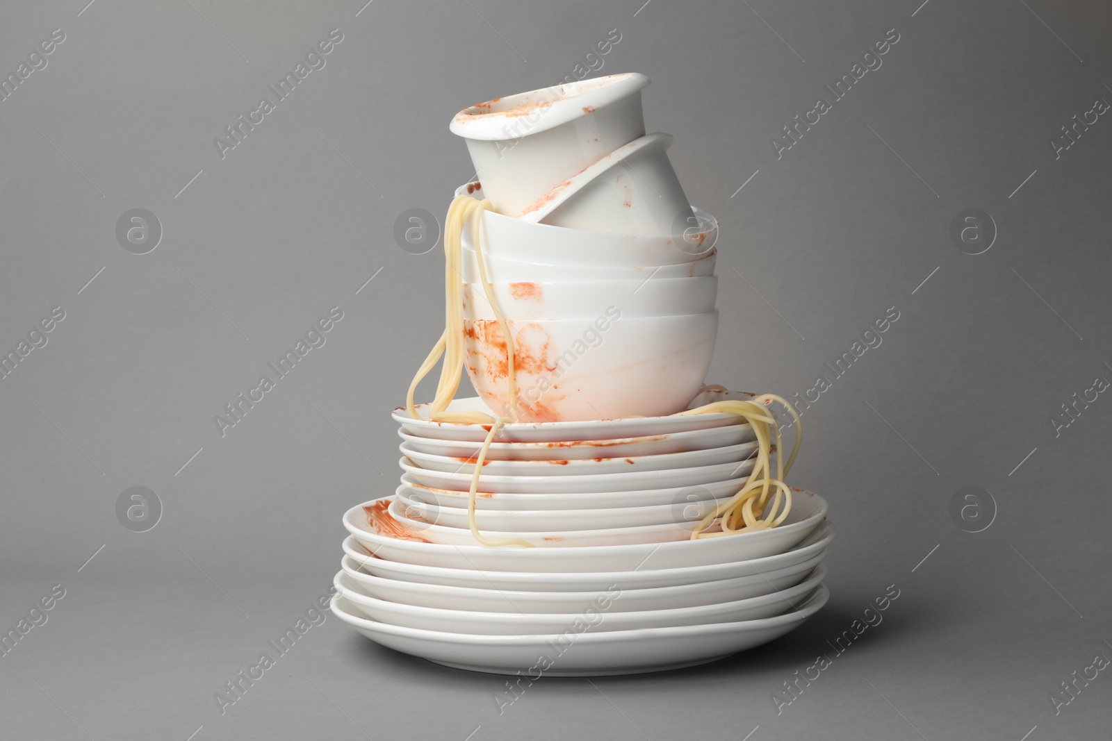 Photo of Set of dirty dishes with spaghetti leftovers on grey background