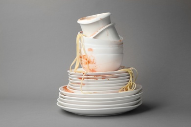 Set of dirty dishes with spaghetti leftovers on grey background