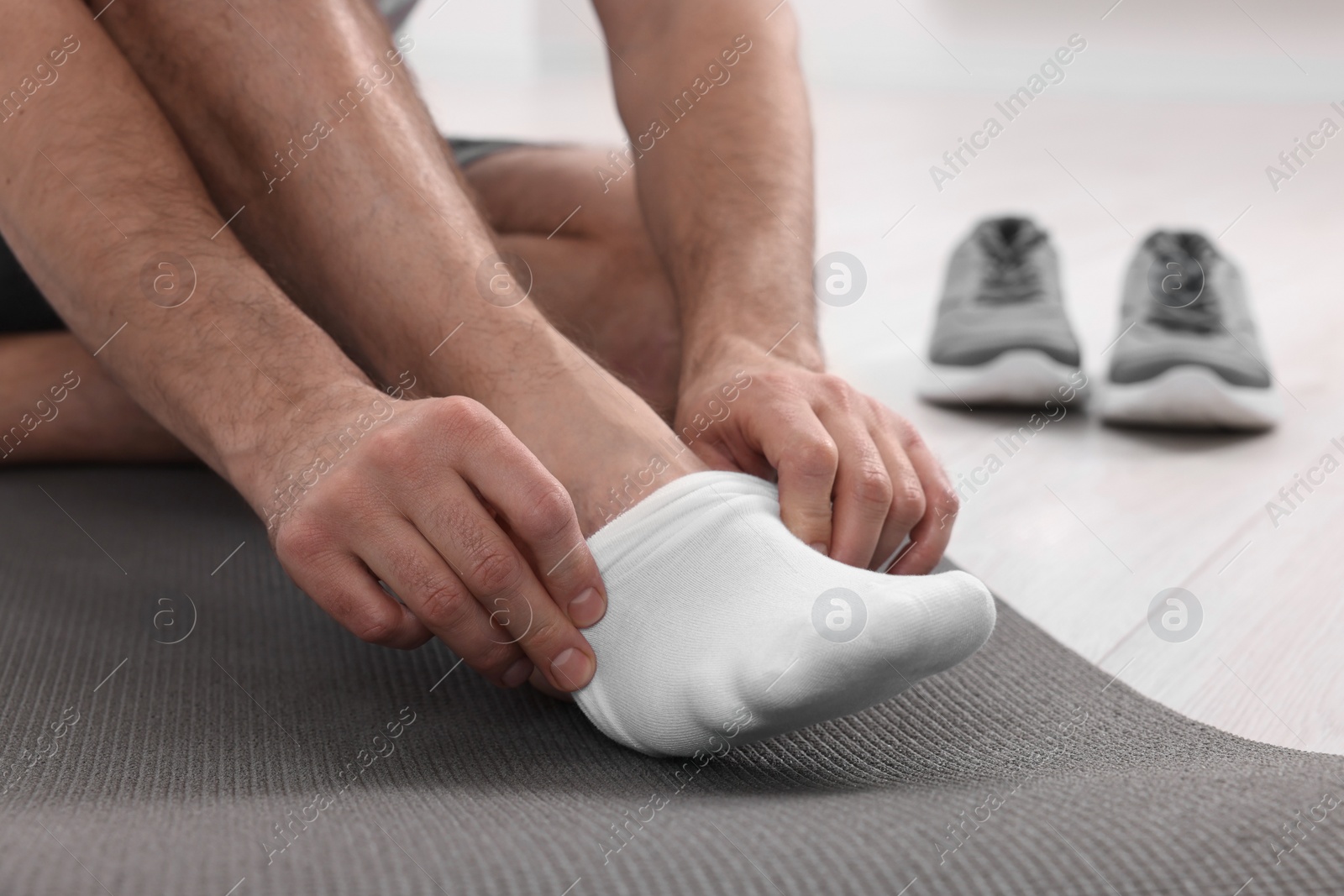 Photo of Man putting on white socks indoors, closeup