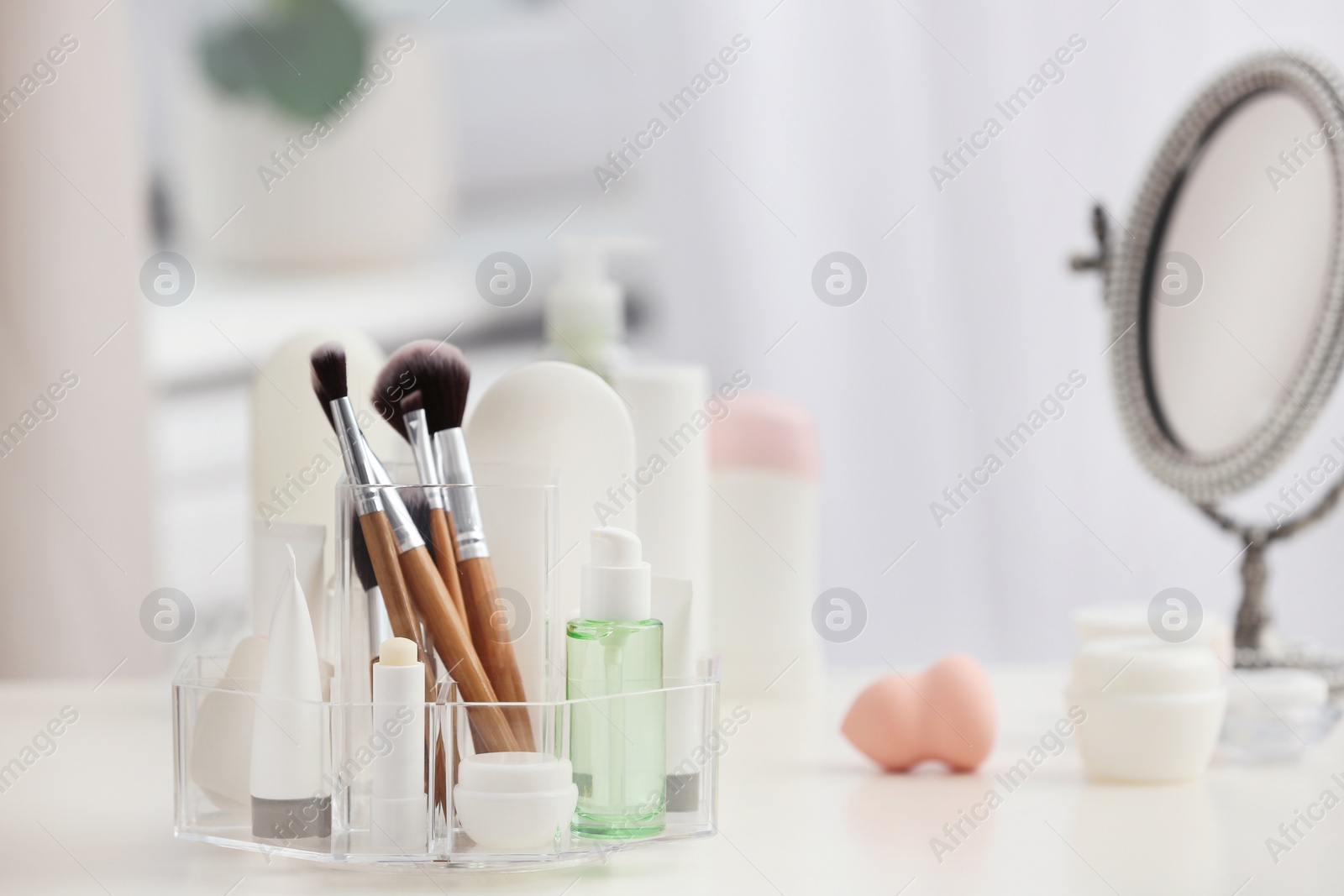 Photo of Organizer with cosmetic products and makeup accessories on table against blurred background. Space for text
