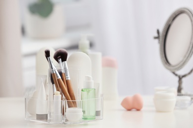 Photo of Organizer with cosmetic products and makeup accessories on table against blurred background. Space for text