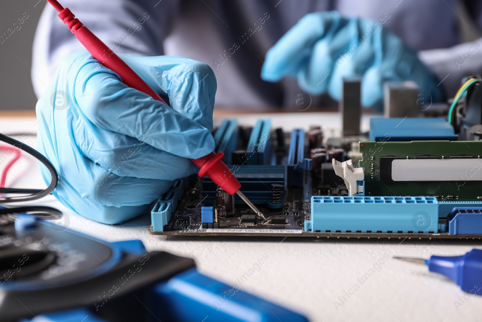 Photo of Technician repairing electronic circuit board at table, closeup