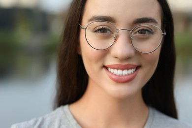 Portrait of beautiful woman in glasses on blurred background. Attractive lady smiling and looking into camera