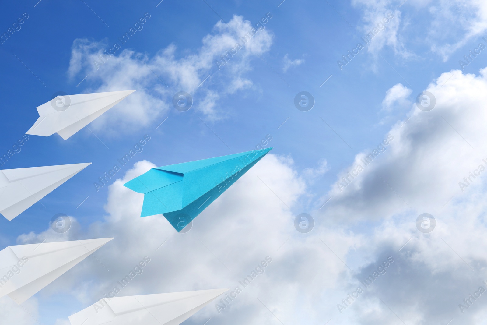 Image of Light blue and white paper planes flying in sky with clouds