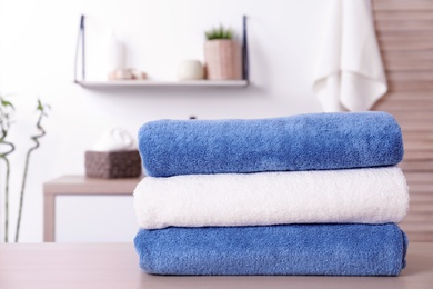 Photo of Stack of fresh towels on table in bathroom. Space for text