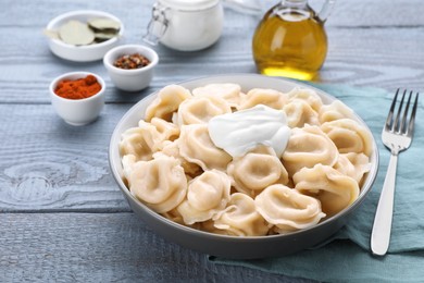 Photo of Tasty dumplings in bowl served on grey wooden table
