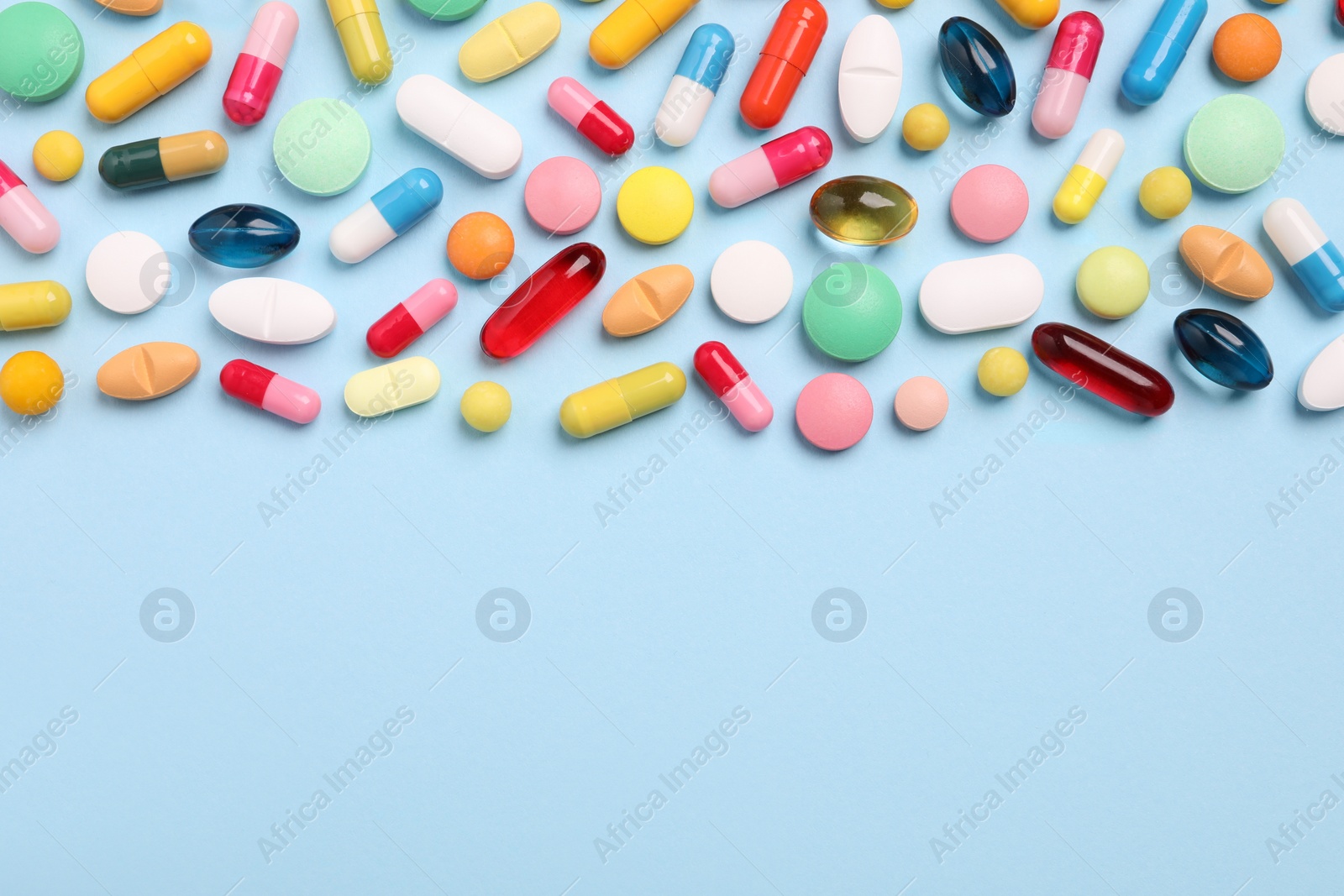 Photo of Many different pills on light blue background, flat lay. Space for text