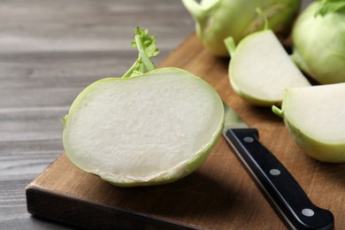 Whole and cut kohlrabi plants on wooden table, closeup