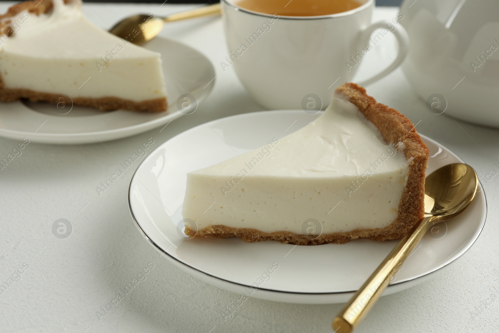 Photo of Piece of tasty vegan tofu cheesecake and spoon on white table, closeup