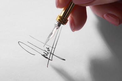 Photo of Woman signing on sheet of paper with fountain pen, closeup