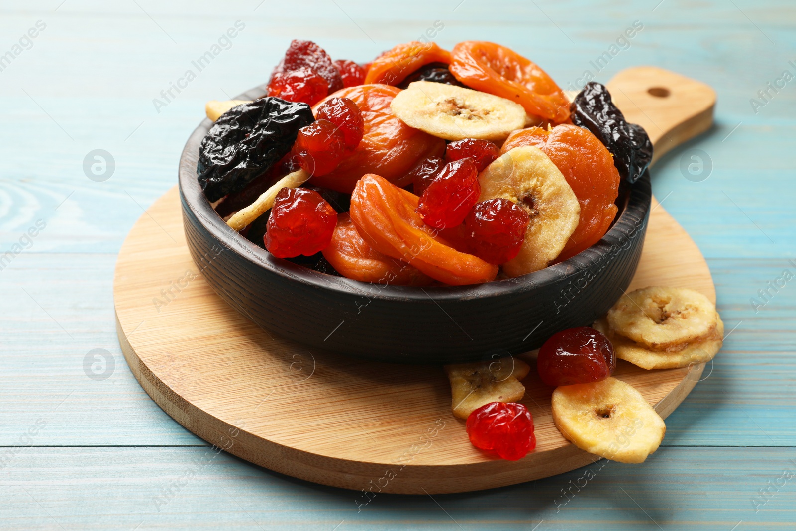 Photo of Mix of delicious dried fruits on light blue wooden table