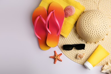 Flat lay composition with sunscreen and beach accessories on white background, space for text