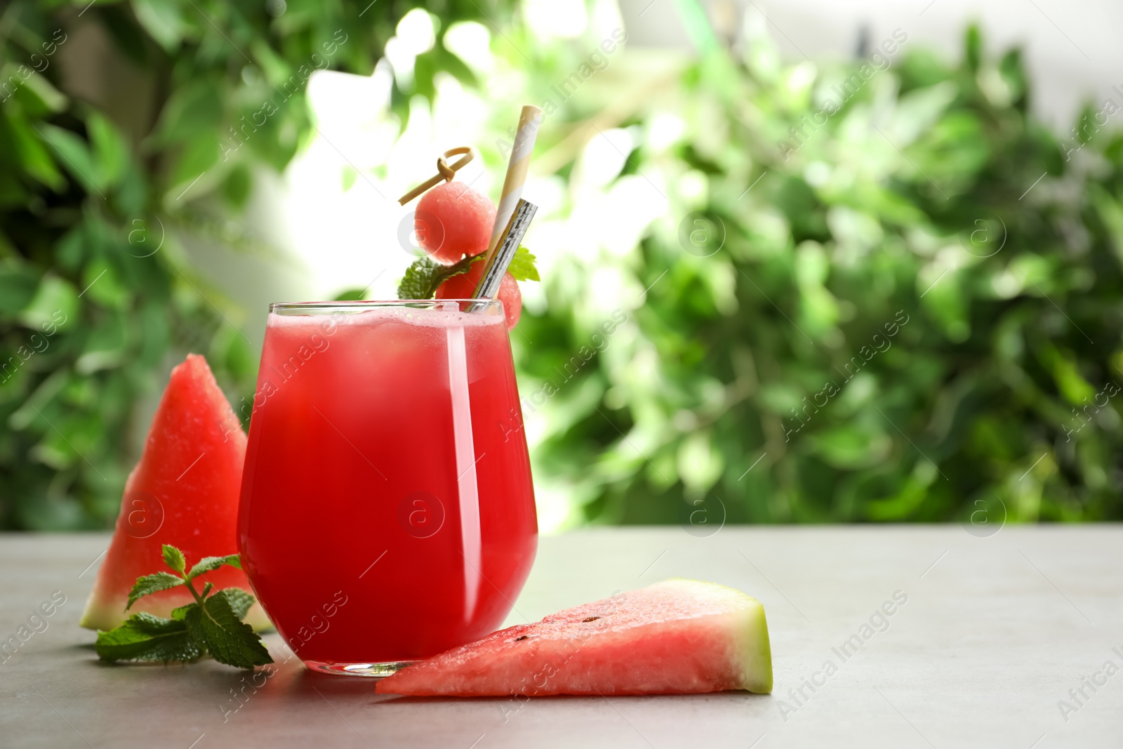 Photo of Delicious fresh watermelon drink on grey table. Space for text