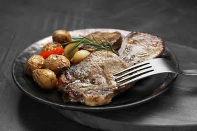 Photo of Tasty beef tongue pieces, rosemary and potatoes on grey table, closeup