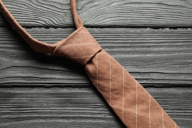 Photo of One striped necktie on black wooden table, top view