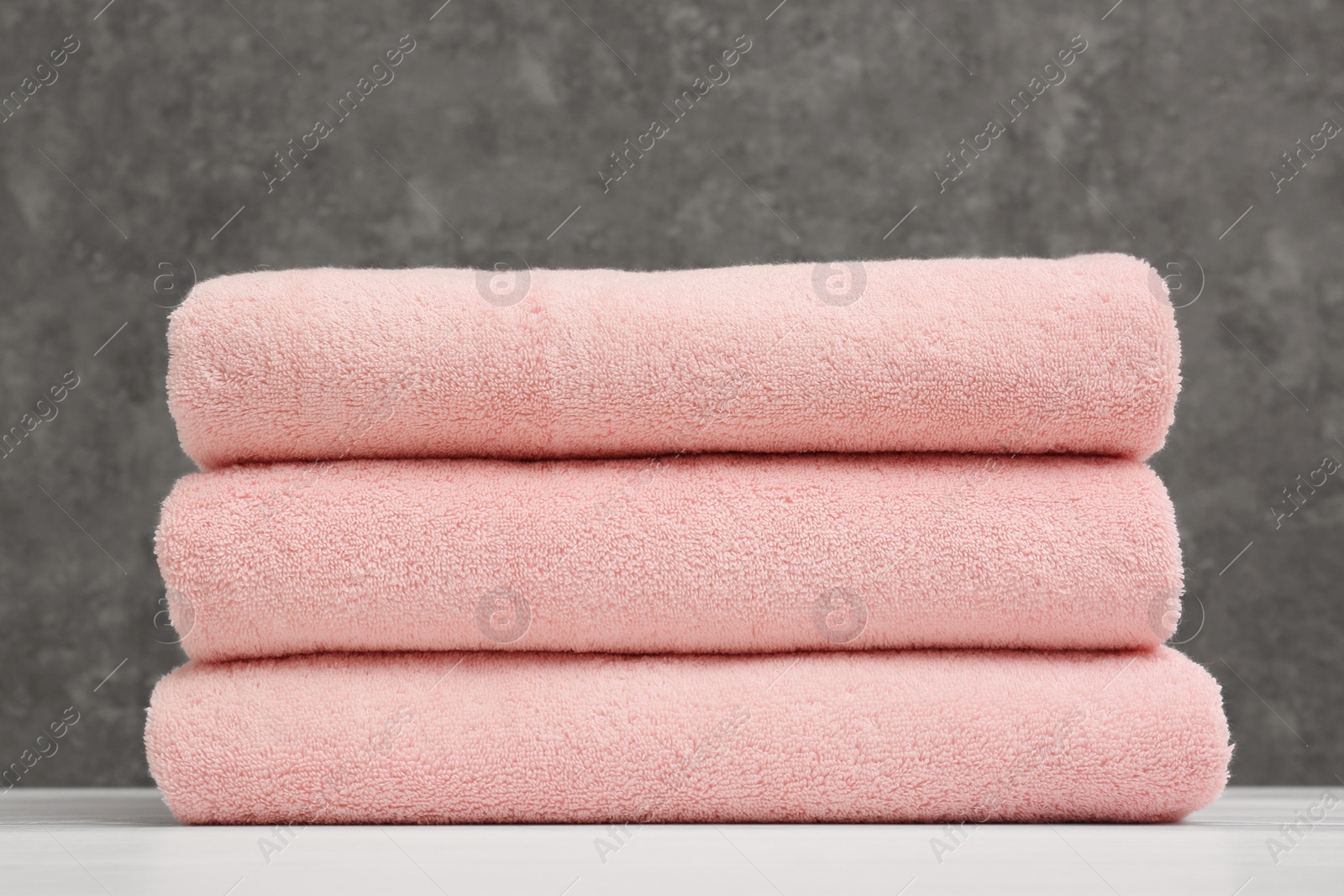 Photo of Stack of soft clean towels on table against grey background