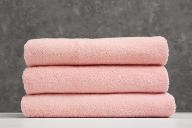 Stack of soft clean towels on table against grey background