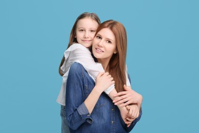 Photo of Portrait of happy mother and her cute daughter on light blue background