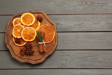 Photo of Flat lay composition with dry orange slices, anise stars and cinnamon sticks on grey wooden table. Space for text