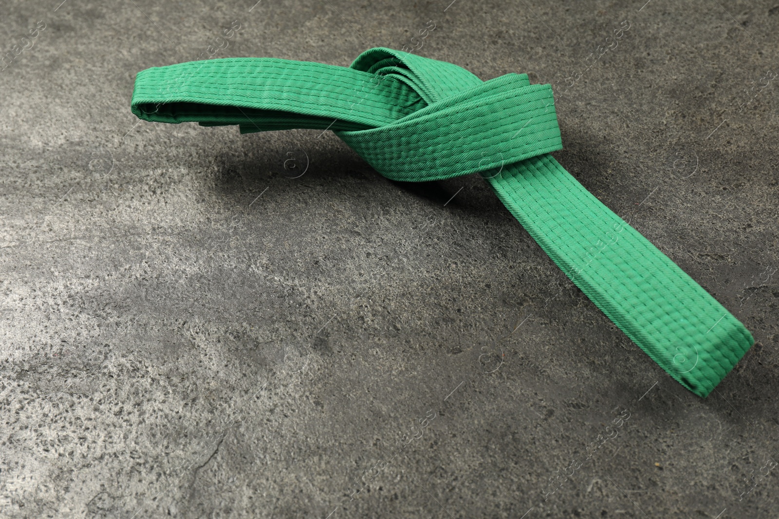 Photo of Green karate belt on gray textured background, space for text