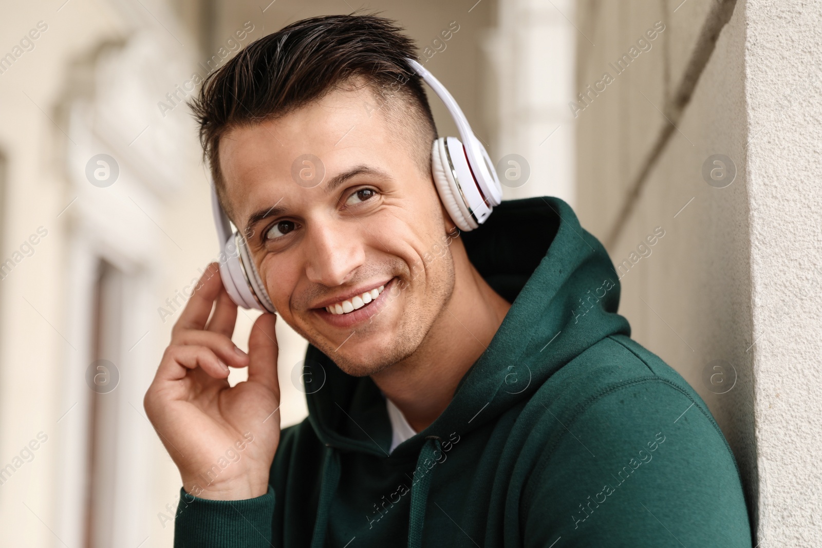 Photo of Portrait of handsome young man with headphones listening to music outdoors