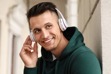 Photo of Portrait of handsome young man with headphones listening to music outdoors