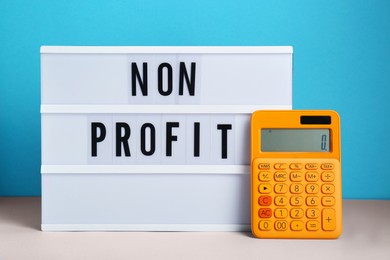 Photo of Lightbox with phrase Non Profit and calculator on white table