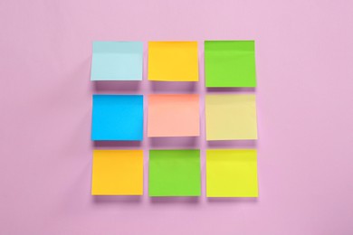 Blank colorful sticky notes on pink background, flat lay