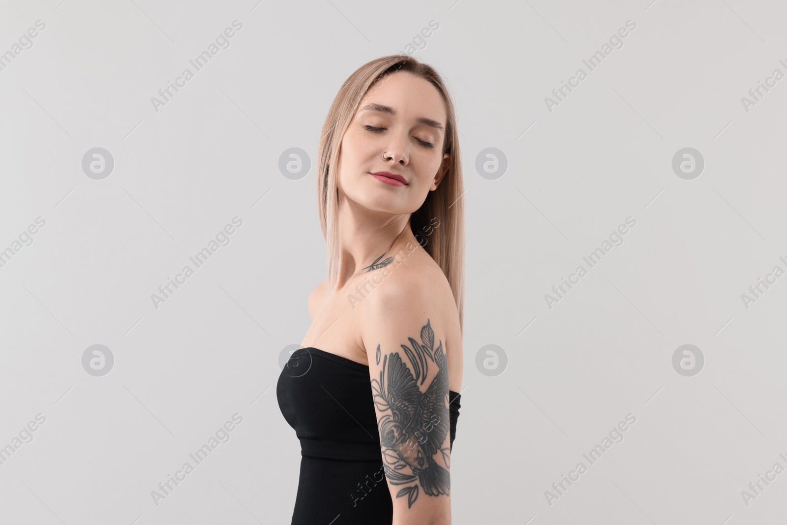 Photo of Portrait of beautiful tattooed woman on light background