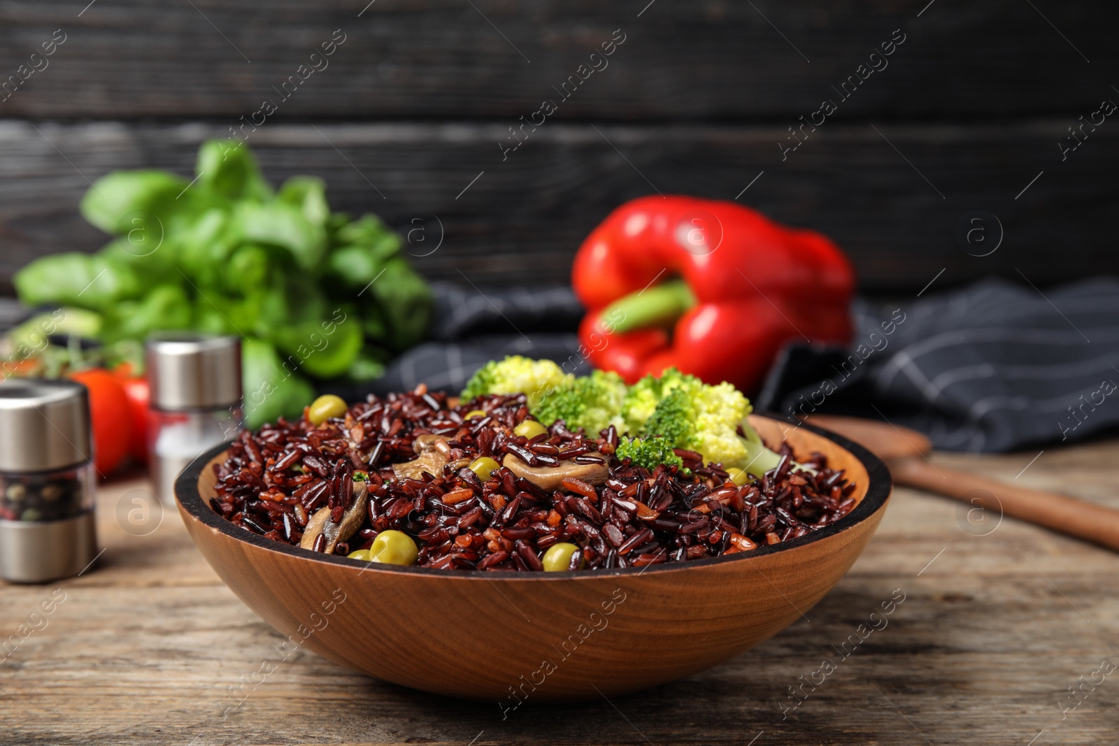 Photo of Bowl with delicious cooked brown rice on wooden table