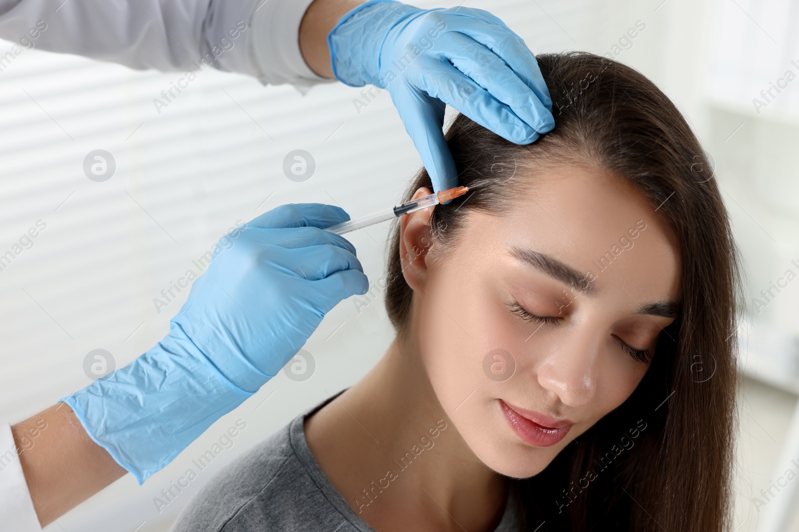 Photo of Trichologist giving injection to patient in clinic, closeup