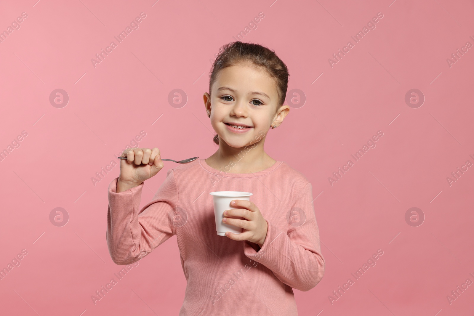 Photo of Girl with tasty yogurt on pink background