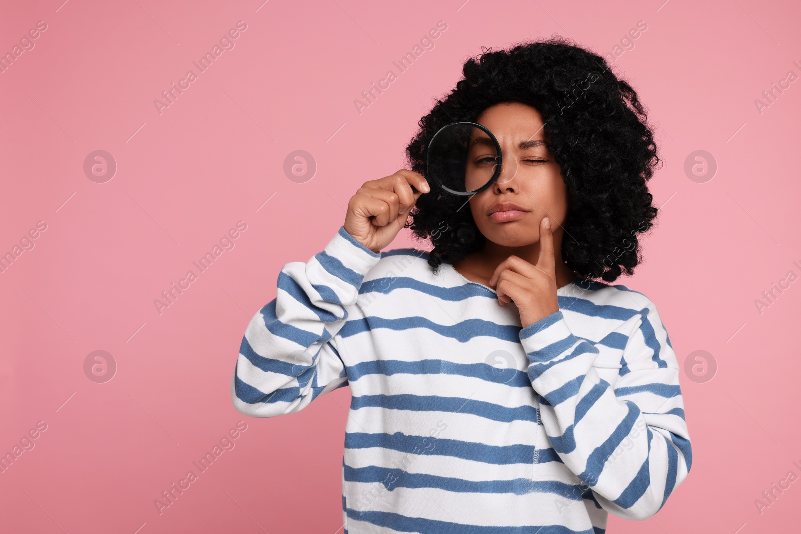 Photo of Woman looking through magnifier glass on pink background, space for text