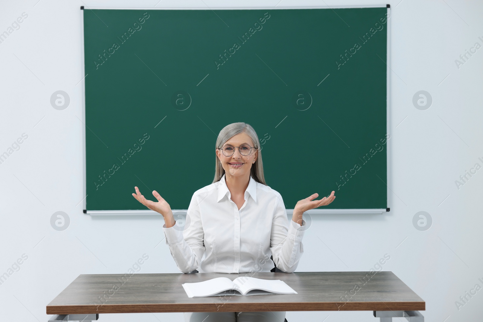 Photo of Professor giving lecture at desk in classroom