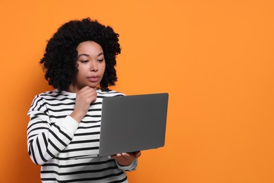 Photo of Beautiful young woman with laptop on orange background. Space for text