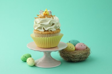 Photo of Tasty Easter cupcake with vanilla cream and festive decor on turquoise background