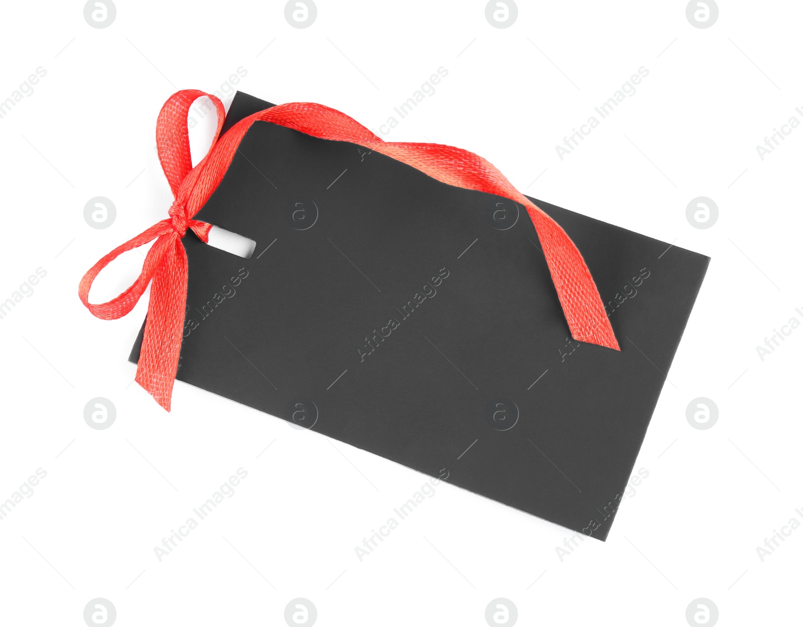 Photo of Blank black gift tag with red satin ribbon on white background, top view. Space for design