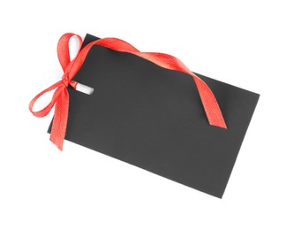 Photo of Blank black gift tag with red satin ribbon on white background, top view. Space for design