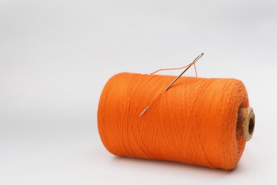 Orange sewing thread with needle on white background