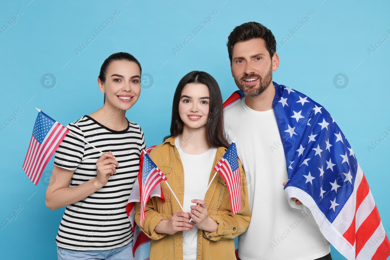 Photo of 4th of July - Independence Day of USA. Happy family with American flags on light blue background