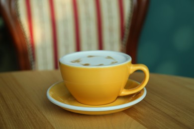 Photo of Cup of delicious coffee on wooden table indoors, closeup