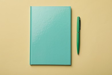 Photo of New turquoise planner and pen on beige background, flat lay