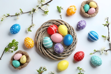 Flat lay composition with painted Easter eggs and blossoming branches on white background