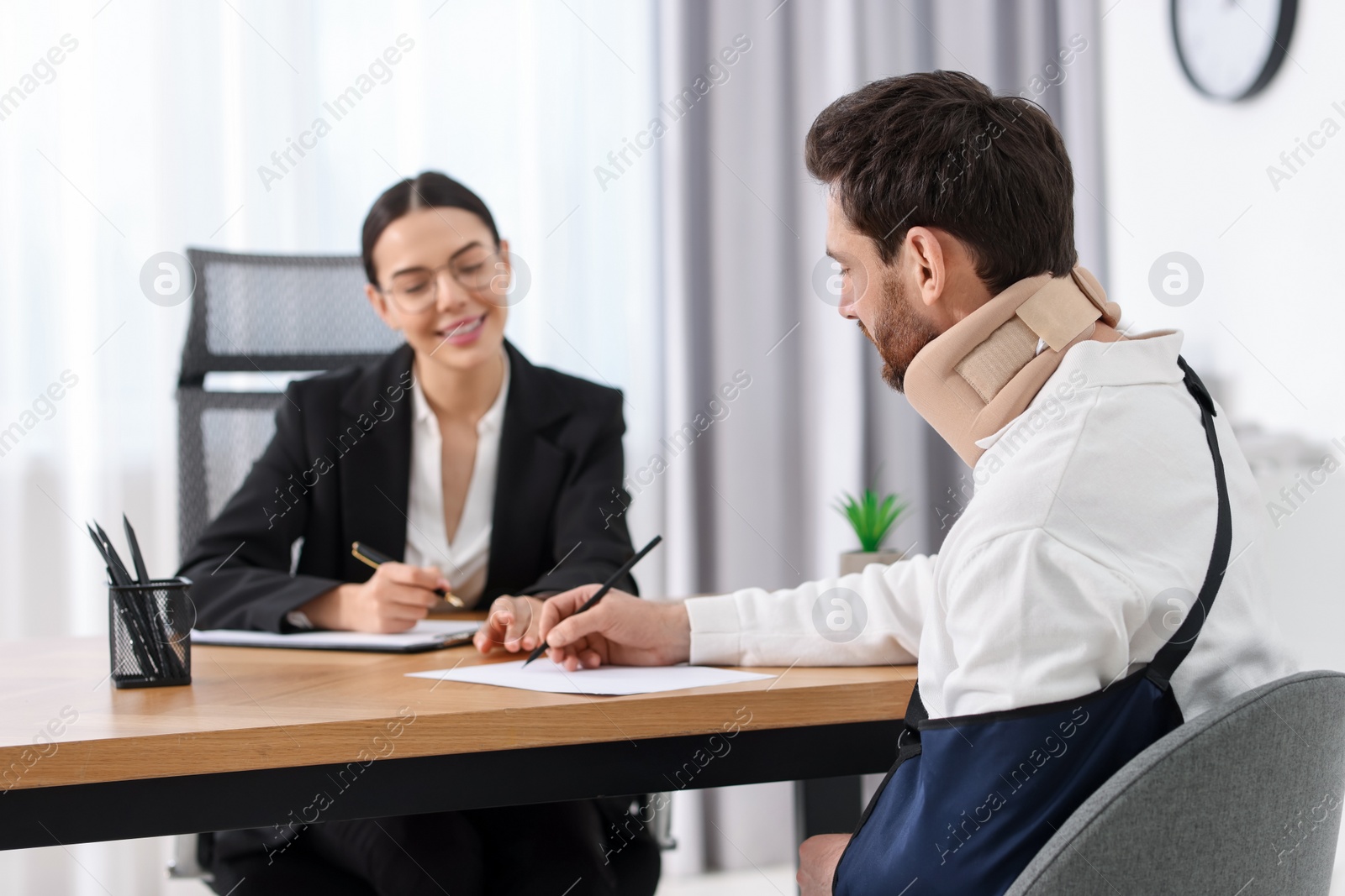 Photo of Injured man signing document in lawyer's office, selective focus