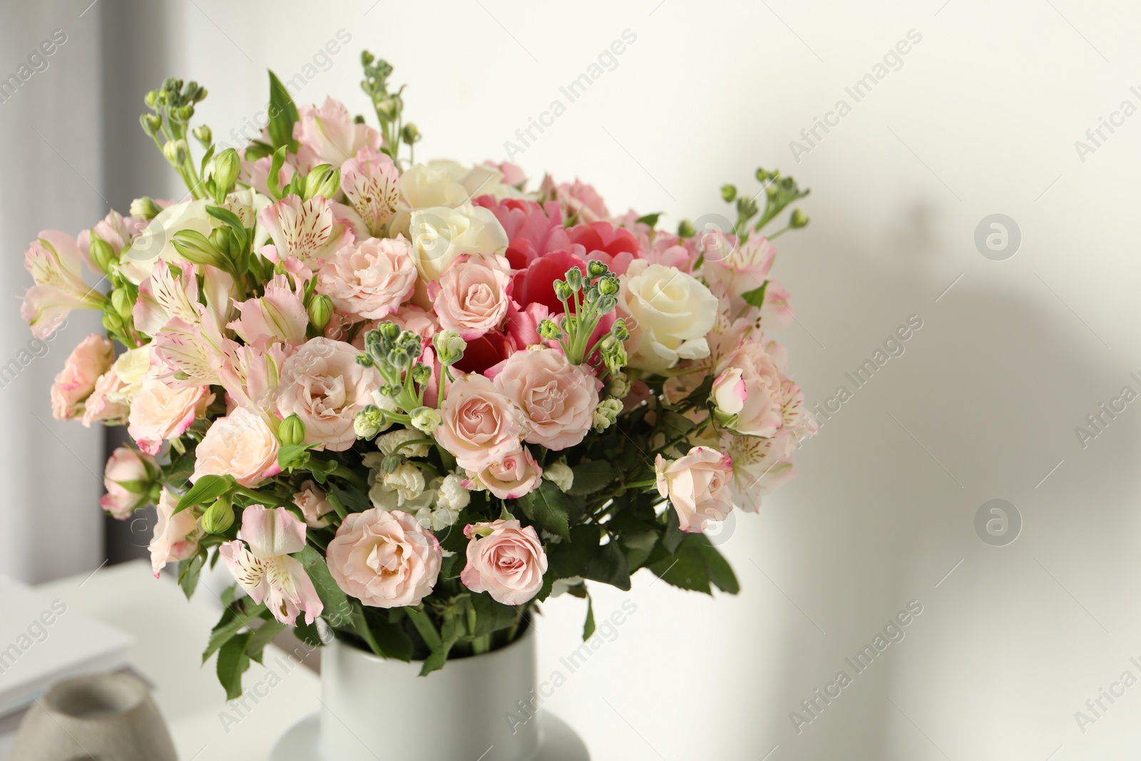 Photo of Beautiful bouquet of fresh flowers in vase near white wall indoors, space for text