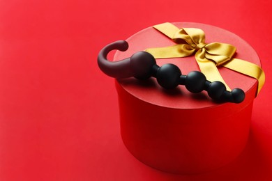 Photo of Gift box with sex toy on red background. Space for text