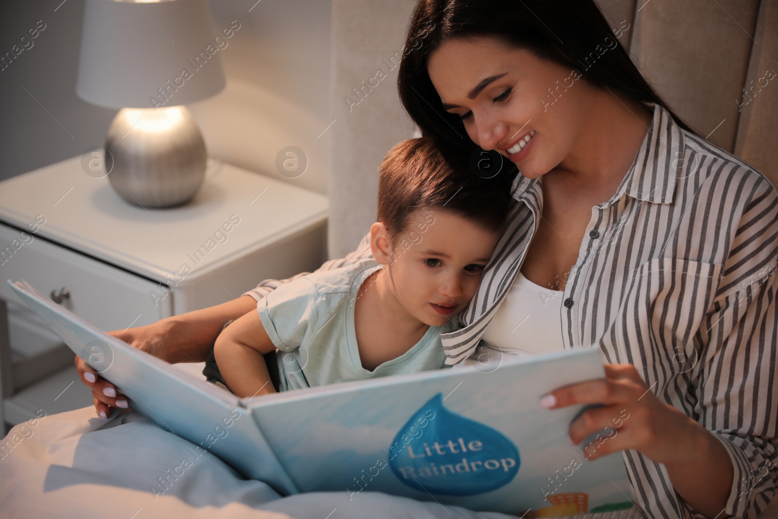 Photo of Mother reading bedtime story to her son at home