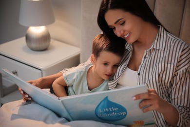 Photo of Mother reading bedtime story to her son at home